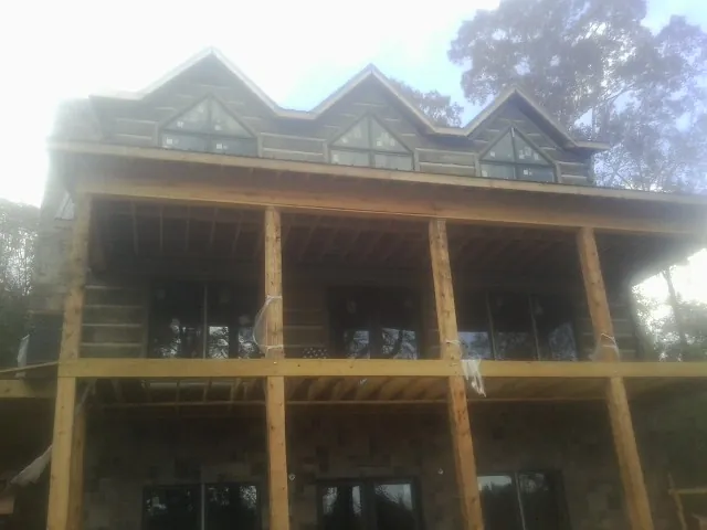 Dormers and porch framing on a large log home under construction — Roof Coating work by our crew in Hope